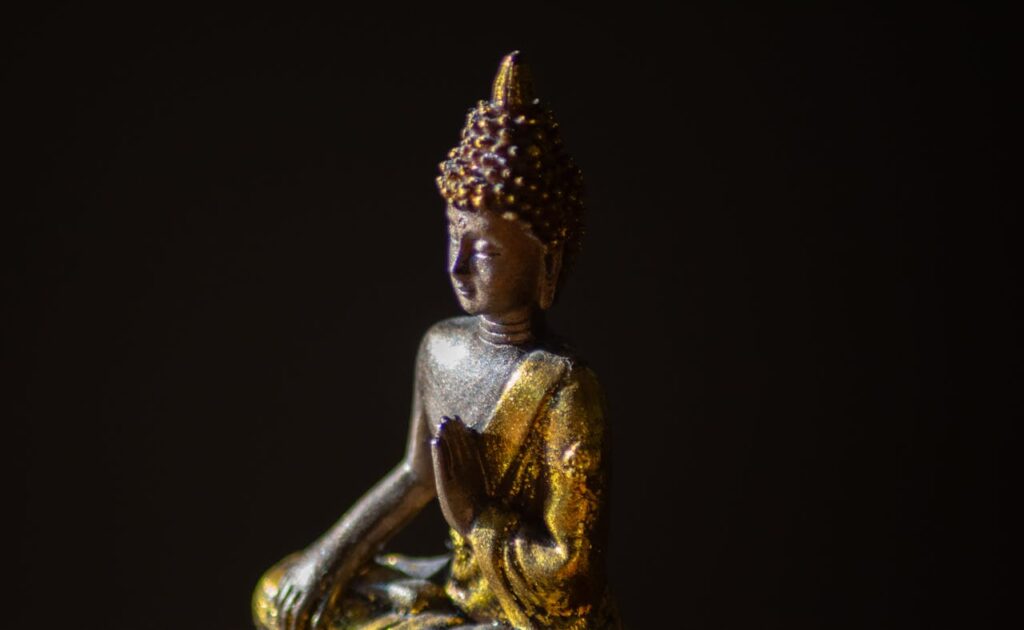 Serene golden Buddha statue illuminated against a dark background, symbolizing peace and spirituality.