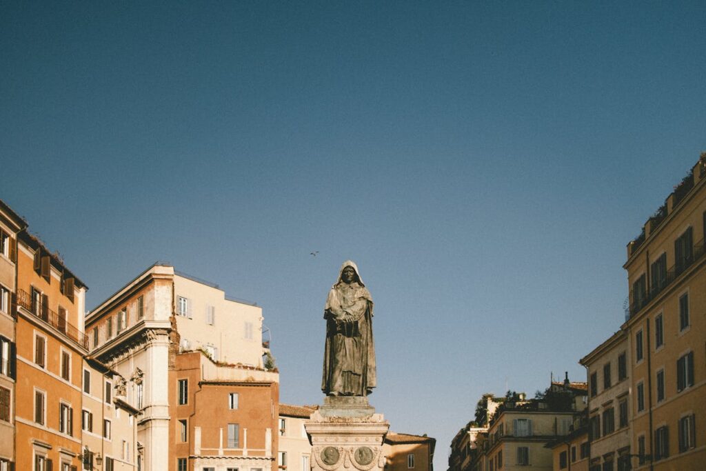 A clear view of the Giordano Bruno statue in Campo de' Fiori, Rome, against a blue sky.